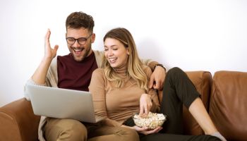 Young couple watching movie at home on laptop