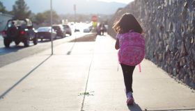 Girl Walking To School Along Busy Street
