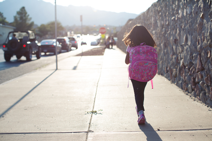 Girl Walking To School Along Busy Street