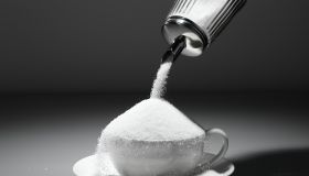 Sugar being poured into tea cup, close-up