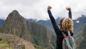 Woman in Machu Picchu celebrating reaching the top of a mountain