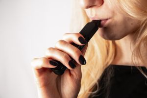 Midsection Of Woman Holding Electronic Cigarette Against White Background