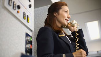 Stewardess instructing passengers on airplane over the loudspeaker
