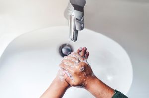 High angle shot of an unrecognizable woman standing alone in the bathroom and washing her hands in the sink