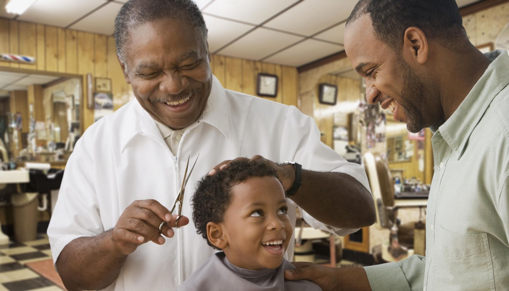 African boy with father getting haircut at barbershop