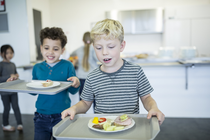 Pupils carrying trays in school canteen