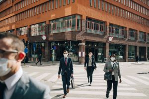 Male and female entrepreneurs crossing street on sunny day in city during pandemic