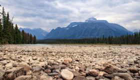 Pebbles in foreground of river bank in dramatic Canadian landscape of Jasper national Park