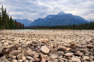 Pebbles in foreground of river bank in dramatic Canadian landscape of Jasper national Park