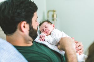 New father holds newborn baby at home, modern manhood