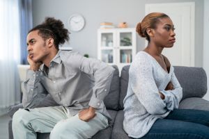 Young multiracial afro couple after conflict, sitting offended and not talking to each other, having relationship problems at home. Spouses after family conflict, breakup, relationship crisis concept