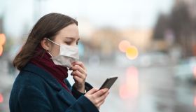 Young girl wearing a protective face mask and checking air pollution with smartphone