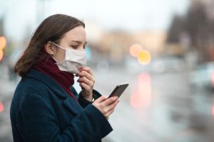 Young girl wearing a protective face mask and checking air pollution with smartphone