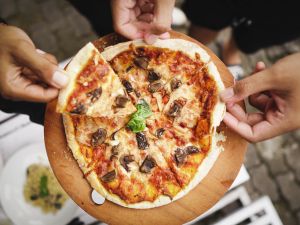 Close-Up Of Hand Holding Pizza