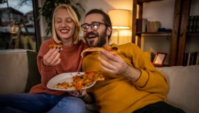 Happy couple eating pizza at home