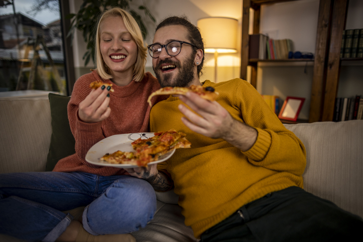 Happy couple eating pizza at home