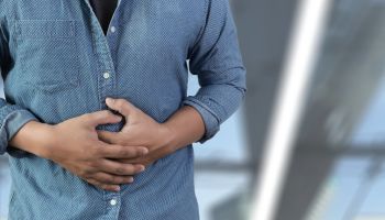 Midsection Of Man Touching Abdomen While Standing Against White Background