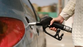 unrecognizable woman using gas pump to add fuel to her car during energy crisis