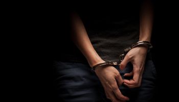 A Girl With Handcuff Over The Dark Background With Copy Space.