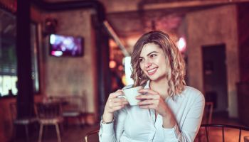 Smiling Female Beauty Enjoying Cup Of Good Coffee While Relaxing In Bar
