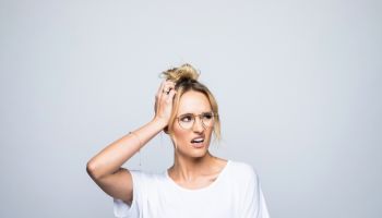 Confused woman looking away while scratching head