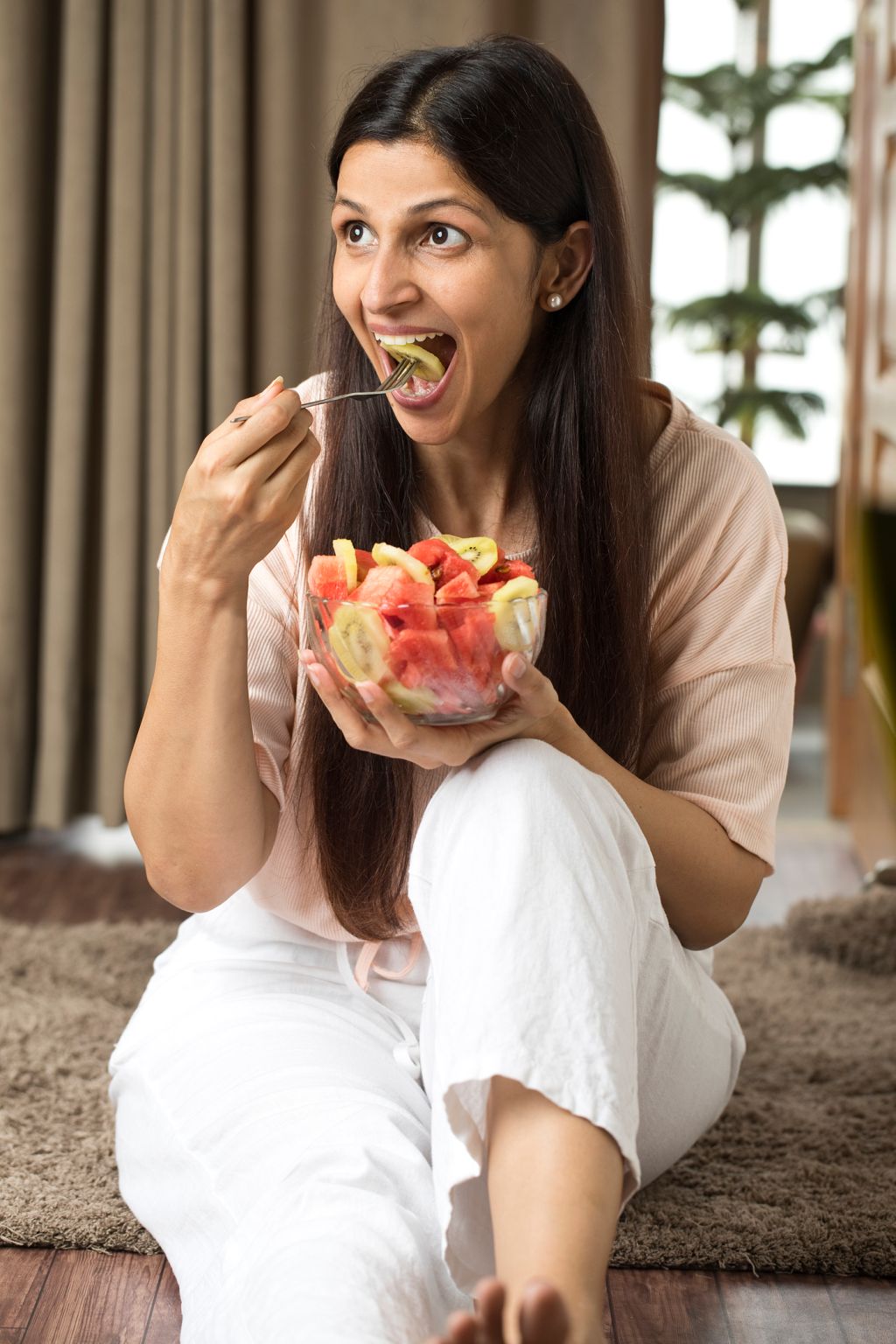 Happy woman eating slice of fresh fruit