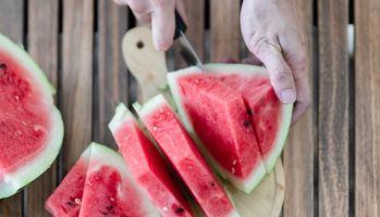 Close-Up Of Man Cutting Watermelon Slices On Table