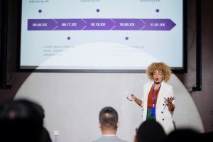 Mid adult black female professional giving presentation in a conference.