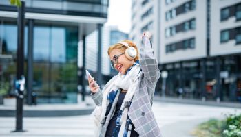Young woman listening a music over headphones in city