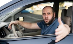 Irritated man driving a car. Irritated angry driver on road