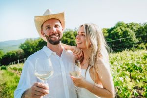 Happy couple with wine standing together at winery