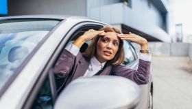 Angry attractive caucasian woman yelling at other drivers while sitting in car.