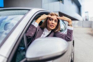 Angry attractive caucasian woman yelling at other drivers while sitting in car.
