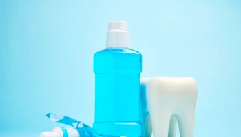 A toothbrush with toothpaste and mouthwash on blue background