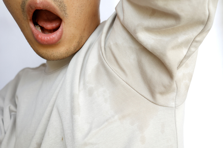 This man's clothes are soaked by underarm sweat.