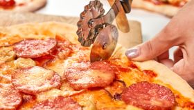 Closeup of a person cutting pizza into slices