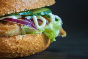 Fresh homemade chicken burger with greens and vegetables dark background