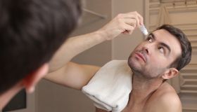 Man applying eyedrops in the bathroom