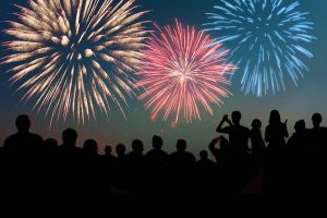 Fourth of July Fireworks Exploding Over Celebrating Spectators in Silhouette