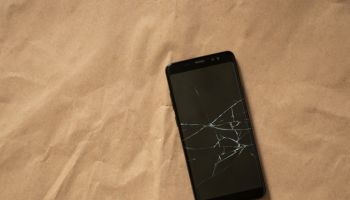 black phone with a cracked screen on a brown background close-up