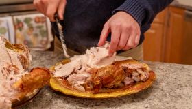 Person getting ready roasted turkey on plate on kitchen table. Thanksgiving dinner