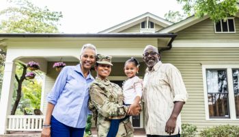 Portrait of female U.S. soldier and multi-generational family in front of home