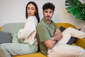 Young couple sitting on a sofa with their backs to each other.