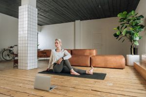 beautiful woman practicing yoga at home online via laptop using internet technology