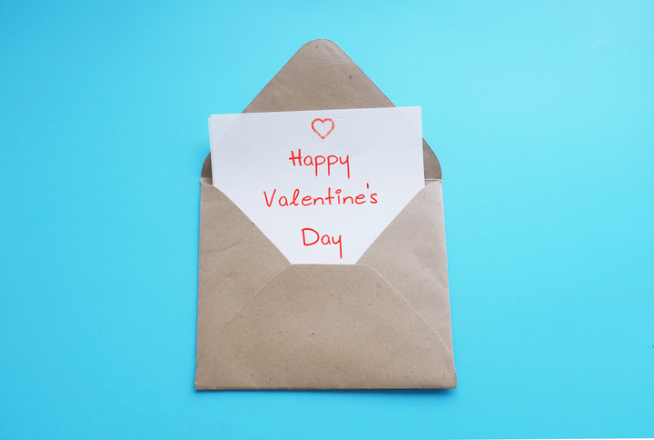 Card in envelope on blue baclground with handwritten text HAPPY VALENTINE 'S DAY, concept of express romantic love and make someone feel special on Valentines's day
