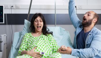 Young couple screaming while sitting on bed at hospital