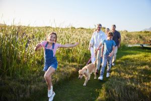 Little girl and her family walking their dog in a nature reserve