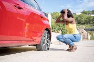 Woman very concerned to find out she has a flat tire on her red car