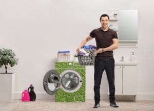 Man with a laundry basket full of clothes standing in a bathroom next to energy efficient waching machine