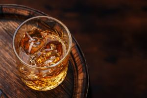 Whiskey glass with ice on a rustic barrel, a classic sip